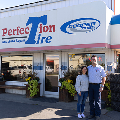 two people standing outside of a tire store