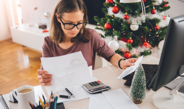 woman looking at bills with christmas tree in background